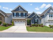 Charming two-story home with a stone accent, a two-car garage and manicured landscaping at 705 Churton Pl, Cary, NC 27518