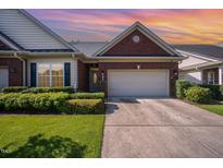Charming brick home featuring a two-car garage, manicured lawn, and beautiful landscaping at 8007 Crookneck Dr, Angier, NC 27501