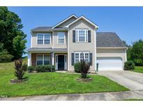 Charming two-story home with a well-maintained lawn, attached garage, and inviting curb appeal on a sunny day at 103 Bermuda Green Dr, Durham, NC 27703