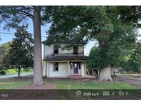Two-story house with a covered front porch and mature trees in the front yard at 12670 School House Rd, Middlesex, NC 27557