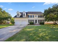 Charming two-story home with a well-manicured lawn, attached two-car garage and mature trees under a beautiful sky at 1805 Abby Knoll Dr, Apex, NC 27502