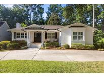 Charming one-story home featuring a white brick exterior, manicured landscaping, and a welcoming covered front porch at 227 W Drewry Ln, Raleigh, NC 27609