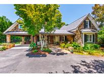 Charming stone home with mature landscaping, metal roof, covered portico, and inviting front entrance at 2707 Anderson Drive Dr, Raleigh, NC 27608