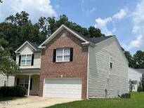 Two-story home with a brick facade and vinyl siding, showcasing its well-maintained exterior and front lawn at 1100 Birkdale Dr, Mebane, NC 27302