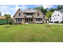 Charming two-story home featuring stone accents, multi-pane windows, manicured landscaping, and a lush green lawn at 1212 Gunnison Pl, Raleigh, NC 27609