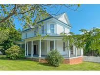 Charming two-story home boasts a wrap-around porch with stately columns and a metal roof at 29 Oak St, Roxboro, NC 27573