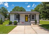 Charming home featuring a bright yellow door, gray accents, and professional landscaping for great curb appeal at 301 Williamson St, Burlington, NC 27215