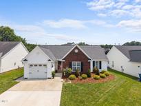 Charming home with brick accents, well-manicured lawn, and attached garage, offering great curb appeal at 302 Slate Dr, Gibsonville, NC 27249