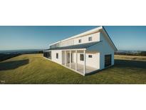 Stunning modern home with white siding, black trim, and a spacious covered porch overlooking scenic views at 345 Wake County Line Rd, Zebulon, NC 27597