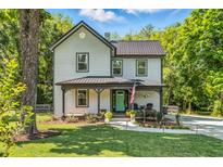 Charming two-story home with a metal roof, welcoming front porch, and freshly landscaped yard at 605 W Holt St, Mebane, NC 27302