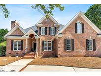 Charming brick home featuring a well-manicured lawn, black shutters, and an inviting covered front porch at 619 Baybush Dr, Raleigh, NC 27615