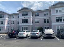 Three-story condominium building featuring light-colored siding and ample parking at 929 Morreene Rd # B-24, Durham, NC 27705
