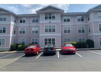 Condo complex featuring light pink siding with white trim, multiple windows, and designated parking spaces at 929 Morreene Rd # C-14, Durham, NC 27705