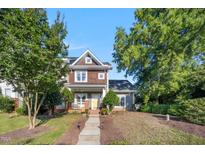 Charming two-story home with a welcoming front porch, mature trees, and well-manicured landscaping at 1009 Porchside Dr, Apex, NC 27502