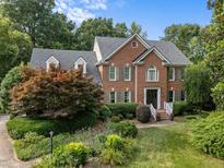 Stately brick home with lush landscaping and a well-manicured lawn presents a welcoming and elegant curb appeal at 102 Alidade Ct, Cary, NC 27513