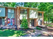 Inviting two-story brick townhome with mature trees, front porch, and well-manicured lawn at 1221 Teakwood Pl, Raleigh, NC 27606
