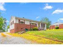 Charming single-story home with a brick facade and a well-maintained lawn under a partly cloudy sky at 1315 Elder Way, Burlington, NC 27215