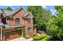 Charming brick home with lush landscaping, wooden garage door, and manicured lawn at 145 Cofield Cir, Durham, NC 27707