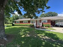 Charming brick home featuring a well-maintained front yard, carport, and inviting front porch at 1828 Fletchers Chapel Rd, Durham, NC 27703