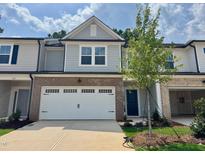 Charming two-story townhome featuring brick accents, a two-car garage, and a welcoming blue front door at 273 Broomside Ave, Raleigh, NC 27603