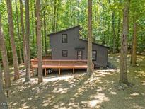 Unique exterior of a modern home featuring a large deck and surrounded by lush trees at 3218 Seven Springs Rd, Hillsborough, NC 27278
