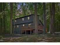 Rear exterior showing a large wooden deck perfect for outdoor entertaining surrounded by tall trees at 3218 Seven Springs Rd, Hillsborough, NC 27278