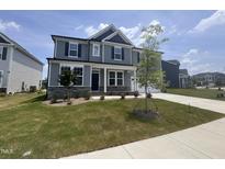 Charming two-story home with gray siding, stone accents, lush green lawn, and inviting covered front porch at 3509 Bailey Lake Dr, Fuquay Varina, NC 27526