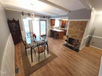 Open dining room and kitchen with exposed wood beams and a stone fireplace at 5805 Mapleridge Rd, Raleigh, NC 27609