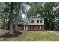 Charming two-story home with brick accents, black shutters and mature trees in a large landscaped front yard at 609 Sloan Dr, Cary, NC 27511