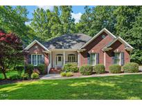 Charming red brick home with a well-manicured lawn, mature trees, and covered porch entrance at 745 Oaks Lane Rd, Timberlake, NC 27583
