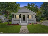 Charming home featuring a welcoming front porch and landscaped front yard at 813 N Main St, Burlington, NC 27217