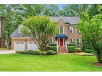 Charming brick home with manicured lawn, mature trees, and a welcoming red front door at 1030 W Sterlington Pl, Apex, NC 27502
