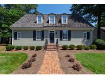 Charming single-story home with a brick walkway, manicured landscaping, and dormer windows at 107 Quarter Path, Cary, NC 27518