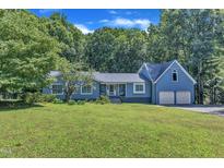 Charming blue home with a two-car garage and mature trees on a well-manicured lawn at 11100 Honeycutt Rd, Raleigh, NC 27614
