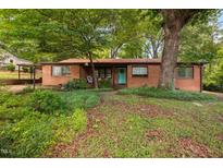 Charming brick home featuring a vibrant blue front door and mature trees in a spacious yard at 1120 E Oak Dr, Durham, NC 27712