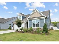 Beautifully landscaped home featuring stone accents, blue siding, and a well-manicured lawn at 125 Alumroot Rd, Holly Springs, NC 27540