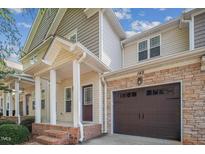Charming townhouse featuring a stone facade, brown garage door, and covered front porch with brick steps at 145 Mariah Towns Way, Garner, NC 27529