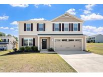 Charming two-story home features beige siding, a two-car garage, and a well-maintained front yard at 16 Powder Ct, Angier, NC 27501