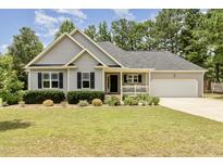 Charming single-story home featuring a manicured lawn, gray siding, and an attached two-car garage at 220 Oxfordshire Dr, Fuquay Varina, NC 27526