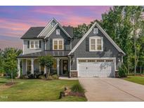 Charming two-story home featuring gray shingles, a manicured lawn, and a covered front porch at 220 W Amber Oak Dr, Selma, NC 27576