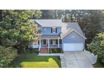 Charming two-story home with a welcoming front porch and a well-manicured lawn surrounded by mature trees at 302 Caraway Ln, Cary, NC 27519