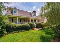 Inviting home featuring a charming front porch, manicured lawn, and beautifully landscaped shrubbery at 3619 Nc-57, Hillsborough, NC 27278