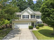 Charming two-story home with a well-manicured lawn, attached two-car garage, and mature trees in a lovely neighborhood at 404 Blooming Meadows Rd, Holly Springs, NC 27540