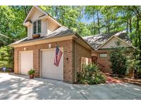 Charming brick home featuring a two-car garage, dormer window, landscaped yard, and American flag at 81106 Alexander, Chapel Hill, NC 27517