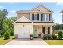 Charming two-story home with a well-manicured lawn, a green door, and an attached one-car garage at 84 Elliot Dr Dr, Clayton, NC 27520