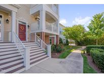 Inviting townhome exterior featuring a charming entrance with a red door, stairs, and a beautiful landscaped walkway at 10330 Sablewood Dr # 104, Raleigh, NC 27617