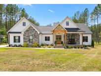Charming home featuring stone accents, a welcoming front porch, and a well-manicured lawn at 1050 Southern High School Rd, Burlington, NC 27215