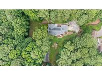 An aerial view of a home nestled among trees with a backyard deck and long driveway at 106 Autumn Cir, Cary, NC 27518