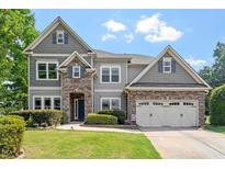 Beautiful two-story home featuring a stone and gray siding exterior and well-manicured lawn at 108 Holly Glen Ct, Holly Springs, NC 27540