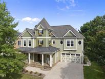 Two-story home featuring a welcoming front porch, garage, and charming architectural details at 1133 Heritage Greens Dr, Wake Forest, NC 27587